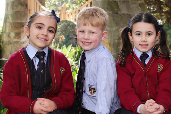 North-Sydney 3 Students smiling on a stone wall.